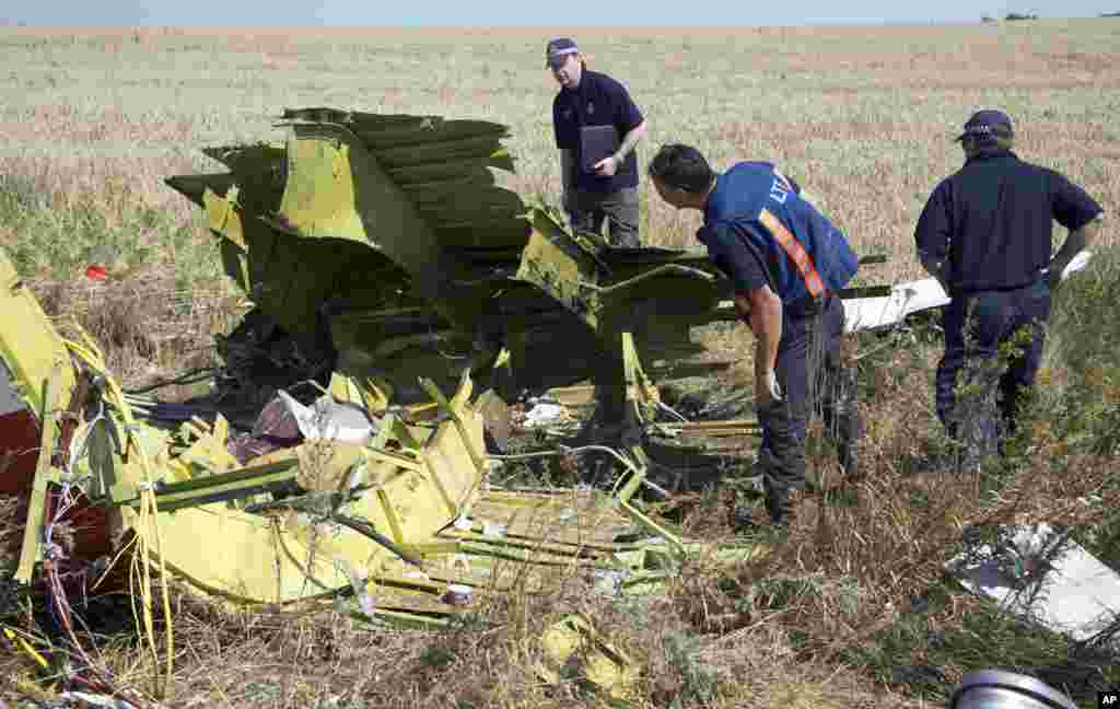 Australian and Dutch experts examine pieces of the Malaysia Airlines plane, in the village of Hrabove, Donetsk region, eastern Ukraine, Aug. 1, 2014. 