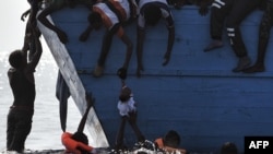 Para migran berupaya menyelamatkan seorang bocah yang tercebur ke laut, sementara mereka menunggu kedatangan regu penyelamat di laut Mediterania, sekitar 12 mil laut sebelah utara dari Libya, 4 Oktober 2016. (Foto: dok).