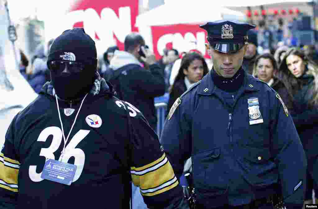 A police officer walks next to a fan at the Super Bowl Boulevard fan zone ahead of Super Bowl XLVIII in New York, Jan. 30, 2014.