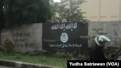 people passing near the wall ISIS symbols and writing support to the establishment of an Islamic state