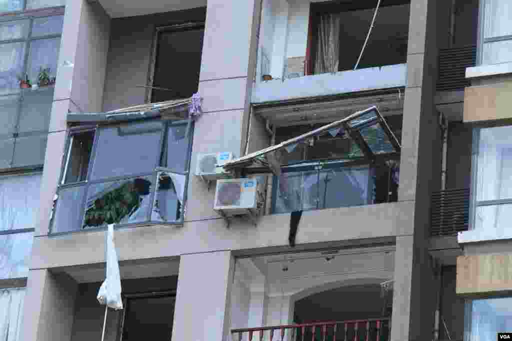 天津爆炸事故现场,核心爆炸区周围多座居民楼窗户被震碎,高速公路桥梁受损,多辆大货车被炸翻,小汽车起火或被砸,多名当地居民仍逗留在事故现场。(美国之音记者东方拍摄)