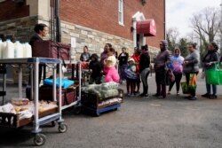 A member of staff gives food to families at the DC Bilingual School after the school was closed due to the global coronavirus pandemic in Washington, March 17, 2020.