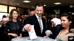 Foto yang dirilis di laman facebook Presiden Suriah ini menampilkan foto Presiden Bashar Assad didampingi istrinyam Asma (kiri), sedang memasukkan surat suaranya ke kotak suara dalam pemilu parlemem di Damaskus, Suriah (13/4). 