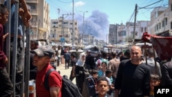 Palestinci u prometnoj ulici u Rafi, u pozadini se vidi dim od eksplozije posle izraelskog vazdušnog udara (Foto: AFP)