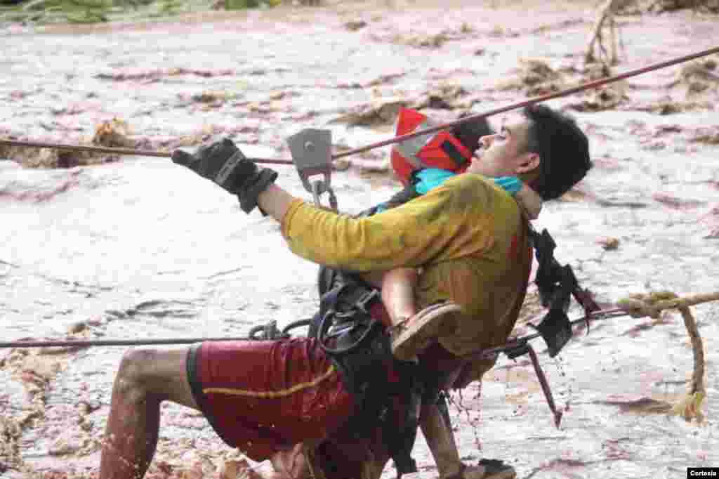 Un bombero hondureño rescata a una niña en Junquillo, Honduras, durante el desbordamiento del río Cececapa. Foto: Cortesía presidencia Honduras.