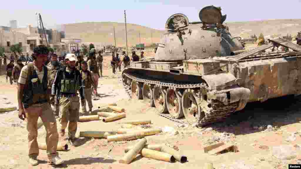 Free Syrian Army fighters inspect munitions and a tank that belonged to forces loyal to Syria's President Bashar al-Assad after they seized Khanasir, August 26, 2013.