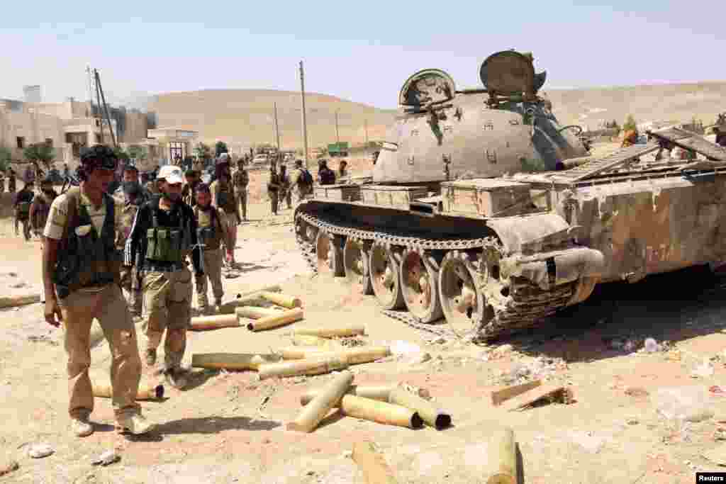 Free Syrian Army fighters inspect munitions and a tank that belonged to forces loyal to Syria's President Bashar al-Assad after they seized Khanasir, August 26, 2013.
