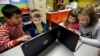 FILE - Second-grader Josh Mercado, left, helps kindergartner Erik Hodges, as second-grader Annabelle Davis, right, helps kindergartner Kaidyance Harris, on programming during their weekly computer science lesson at Marshall Elementary School in Marysville, Wash., Nov. 4, 2015.
