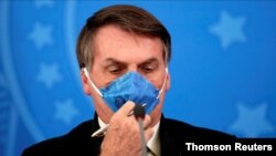 FILE PHOTO: Brazil's President Jair Bolsonaro adjusts his protective face mask at a press statement during the coronavirus disease (COVID-19) outbreak in Brasilia