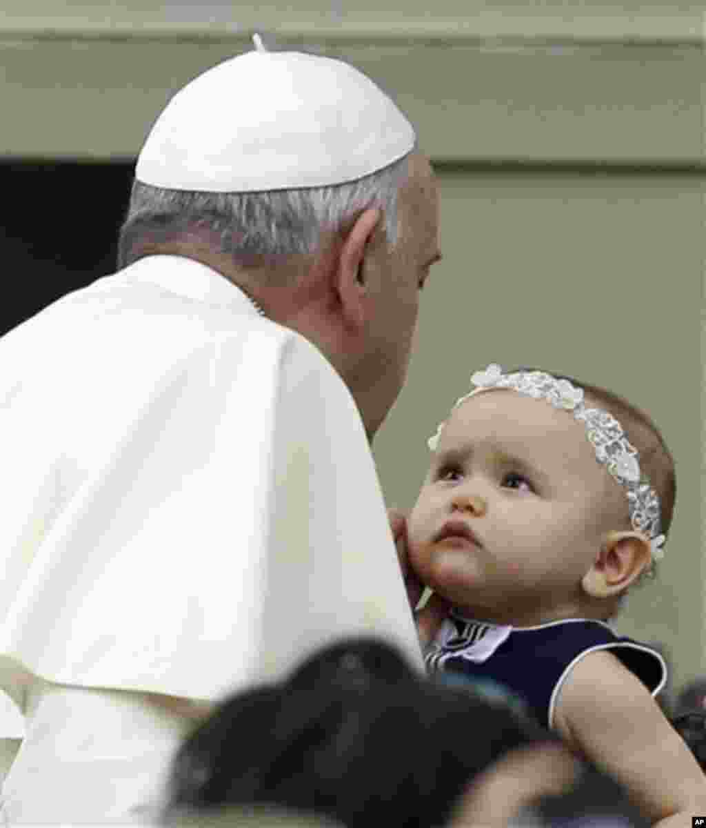 Pape Francois caresse un bébé dans la place Saint-Pierre où il arrive pour assister à l'audience générale hebdomadaire au Vatican, le mercredi 15 octobre 2014 (AP Photo / Gregorio Borgia)