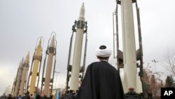 FILE - An Iranian clergyman looks at domestically built surface-to-surface missiles displayed by the Revolutionary Guard in a military show marking the 40th anniversary of the Islamic Revolution, at Imam Khomeini Grand Mosque in Tehran, Iran, Feb. 3, 2019