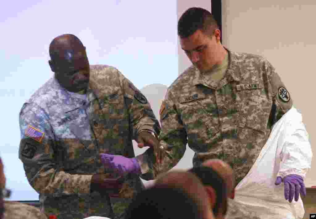 Army Stf. Sgt. Samuel Hines (left) helps Cpl. Zachary Wicker tape gloves to his uniform in Fort Bliss, Texas, Oct. 14, 2014.