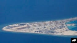 FILE - In this April 21, 2017, photo, an airstrip and buildings on China's man-made Subi Reef in the Spratly chain of islands in the South China Sea are seen from a Philippine Air Force C-130.
