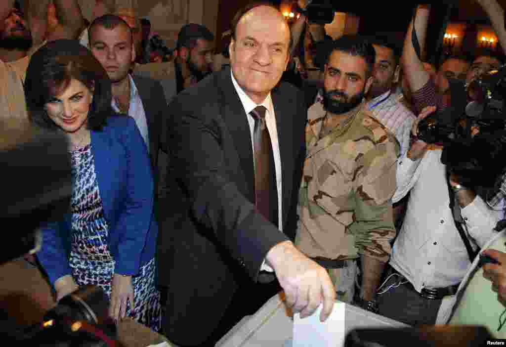 Syria's presidential candidate Hassan al-Nouri accompanied by his wife Hazar casts his vote at polling centrer in Damascus, June 3, 2014.