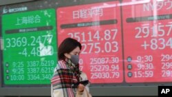 2020年11月10日星期二，一名女子走过东京一家证券公司的电子股票显示屏。