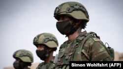 Des soldats rwandais des Forces de défense rwandaises (FDR) et des policiers rwandais se préparent à monter à bord d'un avion "Rwandair" pour une mission militaire au Mozambique à l'aéroport de Kanombe, Kigali, Rwanda, le 10 juillet 2021.
