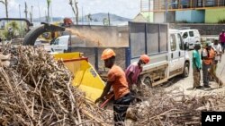 Trabalhadores limpam uma rua na cidade de Mamoudzou, no território francês de Mayotte, no Oceano Índico, que foi devastado por um ciclone, a 29 de dezembro de 2024.