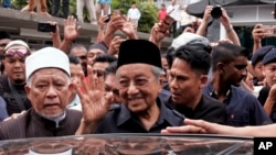 FILE - Malaysian Prime Minister Mahathir Mohamad, center, waves to crowds leaving National Mosque after Friday prayers in Kuala Lumpur, Malaysia, May 11, 2018. 