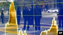 Bayangan orang-orang di papan elektronik sebuah perusahaan sekuritas di Tokyo.