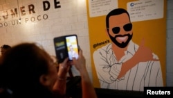 ARCHIVO - Una mujer toma fotografías de un mural que representa al presidente de El Salvador, Nayib Bukele, quien se postula para la reelección, dentro de un restaurante antes de las elecciones presidenciales y del Congreso, en Mejicanos, El Salvador, el 29 de enero de 2024.