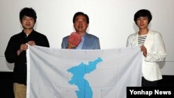 남북한 탁구 단일팀의 전 국가대표 선수 현정화 한국마사회 감독(오른쪽)과 문현성 영화감독(왼쪽)이 지난해 5월 2015 광주 하계 유니버시아드대회 남북단일팀 구성을 기원하는 의미를 담아 한반도기를 강운태 광주시장에게 전달한 후 기념 촬영을 하고 있다.
