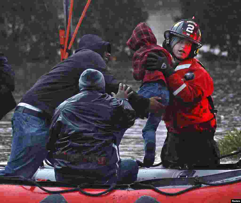 Residents, including a young child, are rescued by emergency personnel from flood waters brought on by Hurricane Sandy in Little Ferry, New Jersey, October 30, 2012.
