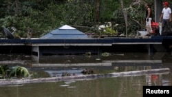 在波多黎各的瓜亚塔卡水坝附近，洪水淹没房屋，人们站在房顶上（2017年9月23日）
