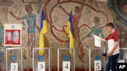Un hombre deposita su papeleta en un colegio electoral durante una elección parlamentaria en Kiev, Ucrania, en julio de 2019. [Foto: Archivo/AP]