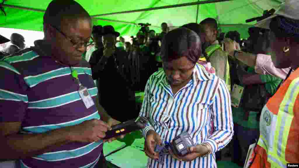 Officials of the Independent National Electoral Commission troubleshoot card readers after they failed to capture President Goodluck Jonathan's card at his polling unit in Otuoke, Bayelsa state, March 28, 2015.