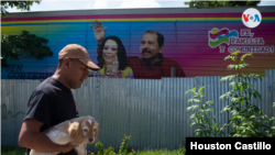 Un nicaragüense camina frente a un pancarta con la imagen del presidente Daniel Ortega y la primera dama Rosario Murilllo. [Foto Houston Castillo/VOA].