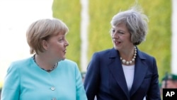 La Chancelière Angela Merkel, à gauche, la Premier ministre Theresa May marchent vers une cérémonie militaire à Berlin, le 20 juillet 2016.