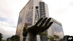 Una escultura de una mano sosteniendo un pozo petrolero se encuentra junto a la petrolera estatal Petróleos de Venezuela S.A. (PDVSA) en Caracas, Venezuela, el 21 de marzo de 2023. (Foto AP/Ariana Cubillos, Archivo)