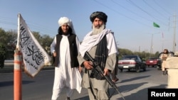 Pejuang Taliban memegang senapan serbu M16 berdiri di luar gedung Kementerian Dalam Negeri di Kabul, Afghanistan, 16 Agustus 2021. (REUTERS/Stringer/File Photo)