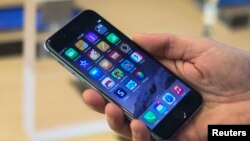 FILE - A customer holds an iPhone 6 on display at the Fifth Avenue Apple store on the first day of sales in Manhattan, New York, Sept. 19, 2014. 