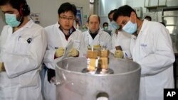 FILE - International Atomic Energy Agency inspectors and Iranian technicians prepare to cut the connections between the twin cascades for 20% uranium enrichment at the Natanz nuclear site near Natanz, Iran, Jan. 20, 2014. 