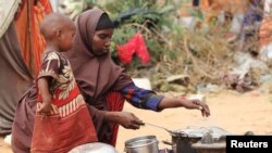  Kadija Mohamed akiwapikia watoto wake chakula katika kambi iliyowekwa kwa ajili ya wakimbizi wa ndani huko Dinsoor, Januari 5, 2012.SOMALIA
