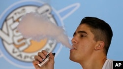 FILE - A smoker exhales vapor from an e-cigarette at the Vapor Spot, in Sacramento, California, in this July 7, 2015, photo.