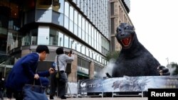 Personas toman fotografías de una estatua de Godzilla promocional de la película 'Godzilla Minus One' en Tokio, Japón, el 11 de marzo de 2024, después de que ganara el Oscar a los mejores efectos visuales durante la entrega de lo 96a edición de los Oscar.