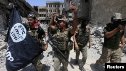 FILE - Members of the Emergency Response Division hold an Islamic State flag that they pulled down as they celebrate in the Old City of Mosul, Iraq, July 8, 2017. Islamic State fighters have mostly been pushed out of Iraq and Syria but are far from defeated, analysts say.