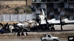Pakistani troops drive past a wreckage of a gutted aircraft at Pakistan Navy base in Karachi, Pakistan, May 23, 2011