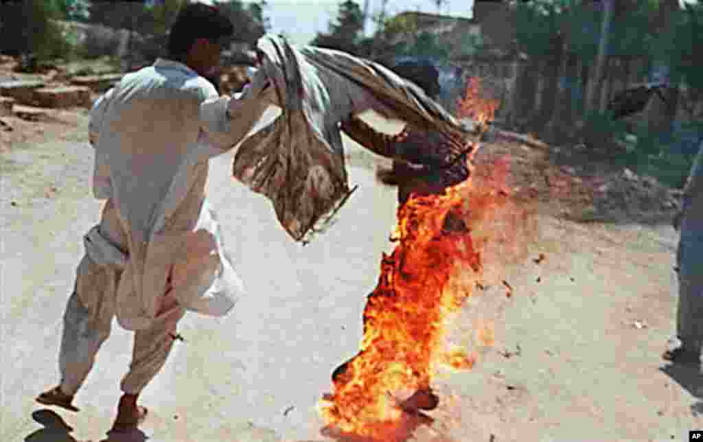 An unidentified man (L) tries to save 26 year-old Aaibunissa (R) who carried out a self-immolation along with another relative woman in front of the Hyderabad special terrorist courts in Karachi. The two women, Zaibunissa and Hakimzadi doused themselves