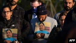 Para kerabat menunjukkan foto orang-orang terkasih yang menjadi korban penembakan massal di fasilitas fedEx, dalam doa bersama di Krannert Park, Indianapolis, Indiana, 17 April 2021.
