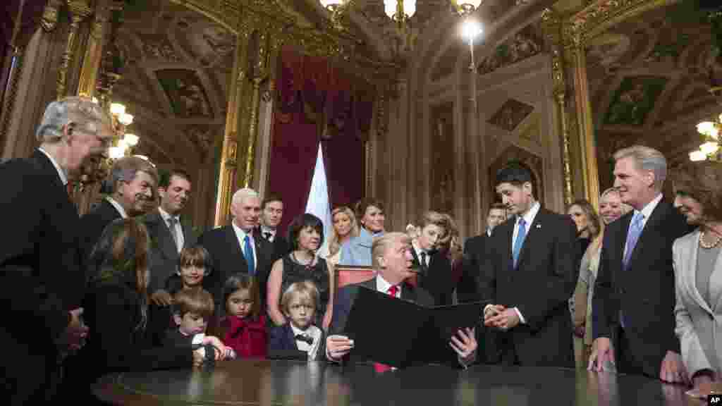 Le président Donald Trump, au centre, se tourne vers le président de la Chambre des représentants, Paul Ryan, entouré du vice-président Mike Pence et des membres de leurs familles, à l'occasion de la signature officielle de la nomination de son cabinet, au Sénat, Washington, 20 janvier 2017.