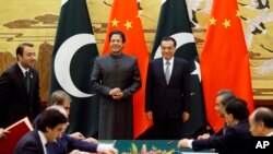 Perdana Menteri China Li Keqiang (kanan) dan Perdana Menteri Pakistan Imran Khan (kiri) menghadiri upacara penandatanganan di Balai Besar Rakyat di Beijing Sabtu, 3 November 2018. (Jason Lee / Pool Photo via AP).