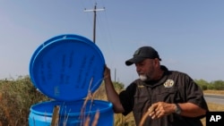 ARCHIVO - EL investigador de la policía del condado Jim Hogg Ruben Garza inspeciona un punto de hidratación para migrantes con garrafas cerradas de agua junto a una carretera en el condado rural de Jim Hogg, Texas, el 25 de julio de 2023. 