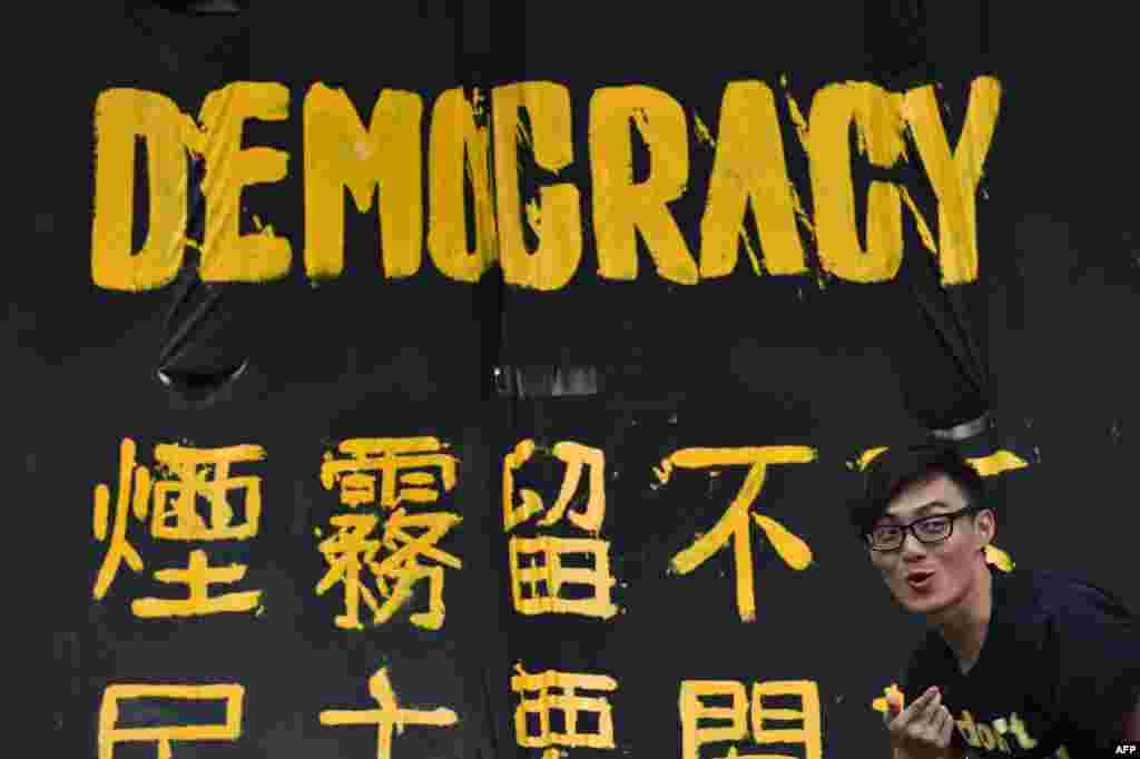 A pro-democracy protester stands next to a banner in Hong Kong, Sept. 30, 2014.