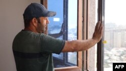 Tajik construction worker Zoir Kurbanov looks out from a window as he renovates a new apartment in Dushanbe on Sept. 17, 2023.