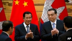 In this photo taken on Jan. 22, 2019, Cambodian Prime Minister Hun Sen, center left, applauds with Chinese Premier Li Keqiang during a signing ceremony at the Great Hall of the People in Beijing, China.