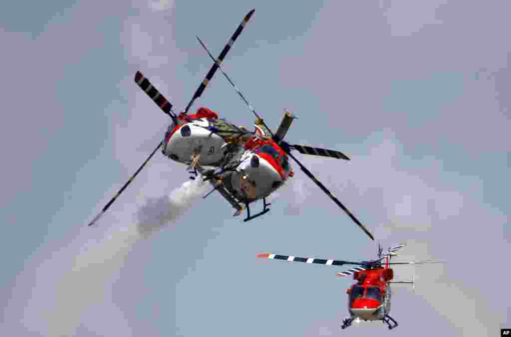 Helikopter Angkatan Udara India saat melakukan penerbangan akrobatik pada pembukaan India Aero 2013 di Yelahanka, pangkalan udara di Bangalore.