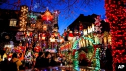 Turis melihat rumah yang dihiasi lampu Natal di kawasan Dyker Heights, Brooklyn, New York, Rabu, 21 Desember 2022. (Julia Nikhinson/AP)